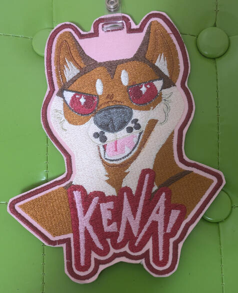 Untitled A brown and white shiba headshot with pink "angry/sassy" eyes grinning with his mouth open. Text reads "Kenai" below him.